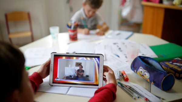 طفل يتابع دروسه عبر الإنترنت بينما يقوم أستاذ بشرح المواد عن بُعد بفرنسا في ظل جائحة «كورونا» (رويترز)