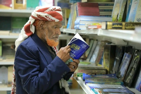 الشيخ المسن وهو يقرأ كتاب الحج والعمرة في معرض مأرب للكتاب