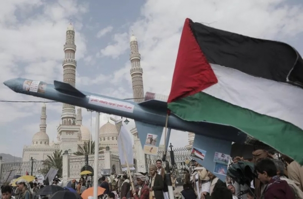 متظاهر يرفع مجسّم صاروخ والعلم الفلسطيني أثناء مشاركته في مظاهرة حاشدة نظّمت تضامنًا مع غزة، في 17 مايو بصنعاء